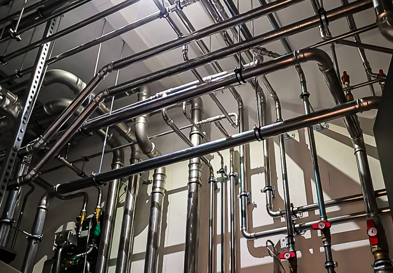 Sorgfältig verlegte Edelstahl-Rohrinstallation in einem Technikraum
